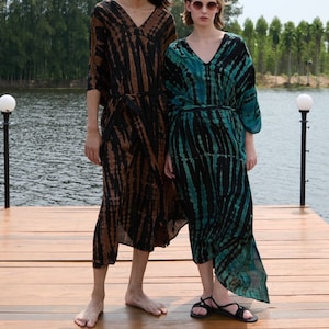 May include: Two models wearing long, tie-dye patterned dresses. The dress on the left is brown and black, while the dress on the right is teal and black. The model on the left is 6'2" (190 cm) tall and the model on the right is 5'7" tall.
