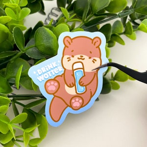 Boisson Wotter | Adorable loutre autocollant en vinyle découpé mat ou holographique