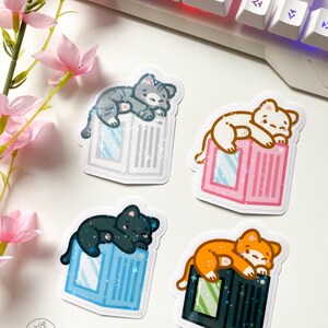 May include: Four stickers featuring cartoon cats sleeping on top of different coloured computer components. The cats are grey, black, white, and orange. The computer components are blue, pink, green, and grey.