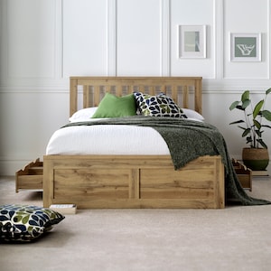 May include: A wooden bed frame with a slatted headboard and footboard. The bed has two drawers on each side and a green and blue patterned throw blanket on top.