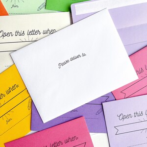 May include: A white envelope with the text "Please deliver to." printed on the front. The envelope is surrounded by other colorful envelopes with the text "Open this letter when" printed on them.