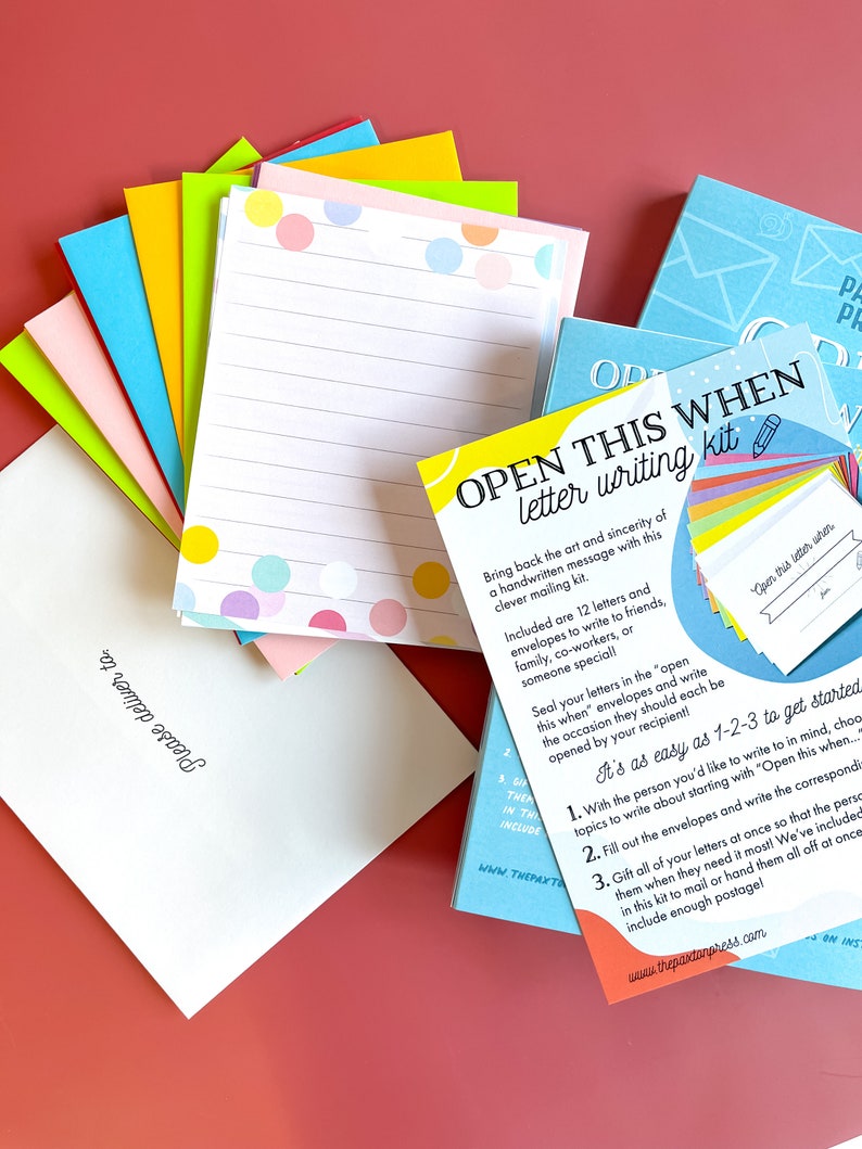 May include: A colorful letter writing kit with 12 envelopes and letters, a guide, and the text "Open this when" on the front. The kit is designed to encourage handwritten letters and includes instructions on how to use it.