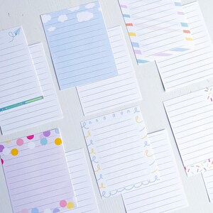 May include: A set of eight lined note cards with different decorative borders. The borders include clouds, confetti, stripes, and a wavy line. The cards are all white with blue lines.