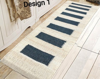 May include: A white and gray striped rug with the text "Design 1" in the upper left corner. The rug is made of natural fibers and has a woven texture.