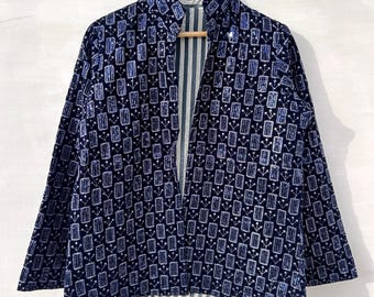 May include: A long-sleeved jacket featuring a dark blue fabric with a repeating white and light blue geometric pattern of rectangles and small floral-like stems. The jacket has an open front, a high collar, and a visible inner lining with vertical stripes.