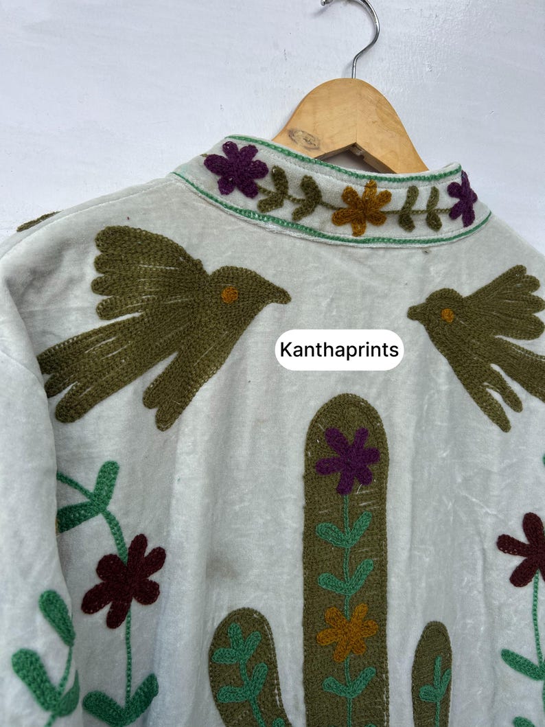 May include: Off-white jacket with embroidered details. Features two olive green birds, a cactus, and floral designs in shades of green, purple, and orange. The text "Kanthaprints" is visible.