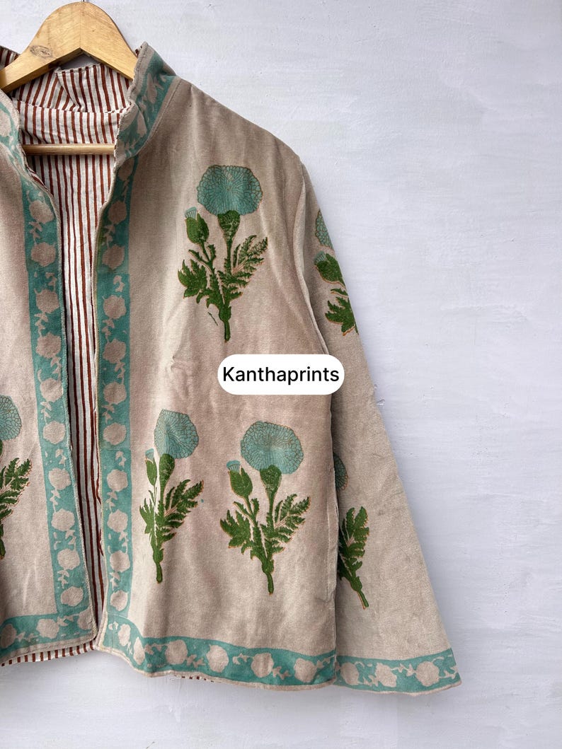 May include: Beige jacket with a floral print in teal and green. The jacket has a teal border and a striped brown and white lining. The text "Kanthaprints" is visible on the jacket.