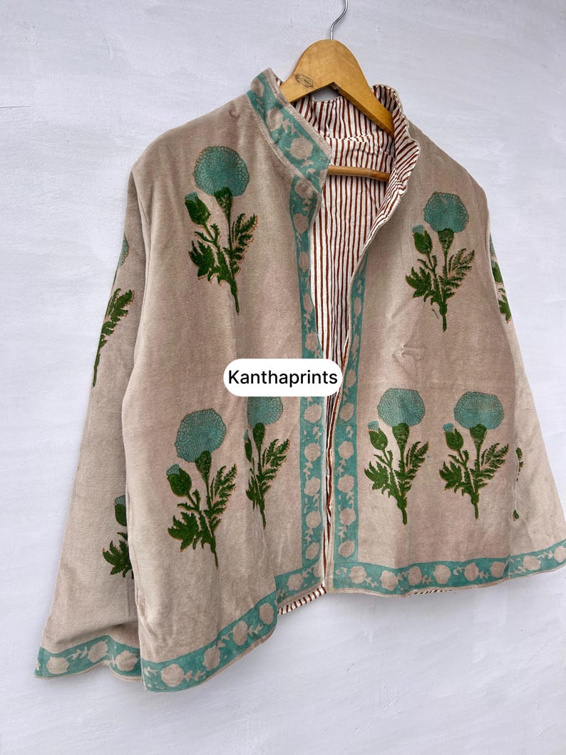 May include: Beige jacket with a floral design in teal and green. The jacket has a teal border and a striped interior. The text "Kanthaprints" is visible on the front of the jacket.