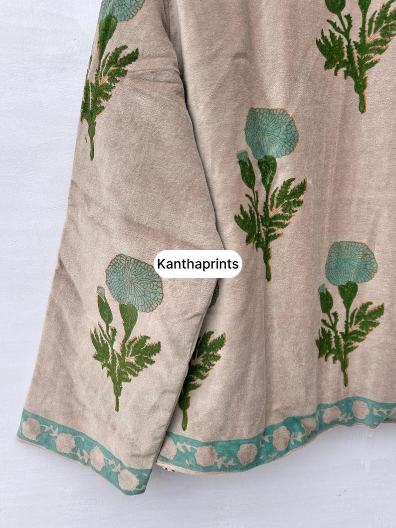 May include: Beige fabric with a floral pattern in teal and green. The design features stylized flowers and leaves, with a teal border along the edge. The text "Kanthaprints" is visible on the fabric.