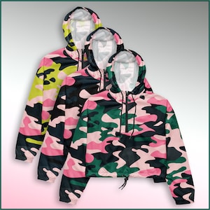 May include: Three hooded jackets in a pink, green and black camouflage pattern. The jackets are cropped and have a drawstring at the waist.