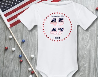 May include: White baby onesie with a red, white, and blue American flag design. The onesie has the text "November 5th" and the numbers "45 47" with a circle of red stars around them. The text "2024" is below the numbers.