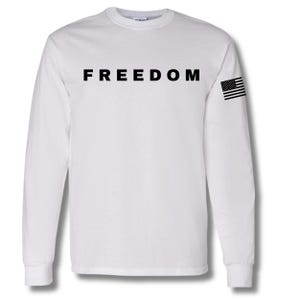 May include: White long-sleeve shirt with the word "FREEDOM" printed in black across the chest. An American flag graphic is on the left sleeve. The shirt is made of a soft, comfortable material.