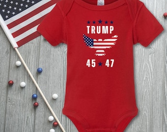 May include: Red baby onesie with a white eagle graphic and the text "TRUMP 45*47" printed on the front. The eagle has an American flag design.