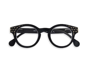 Könnte beinhalten: Schwarze runde Brille mit goldenen Nieten um den Rahmen. Die Brille hat klare Gläser und der Text "K501" ist auf dem rechten Glas aufgedruckt.