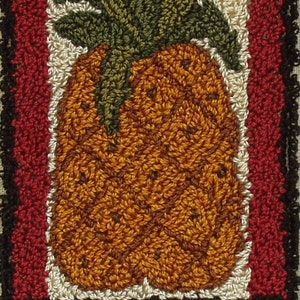 May include: A red, white, and black needlepoint welcome sign with a pineapple design. The pineapple is brown, orange, and green.