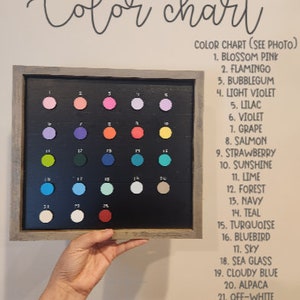 May include: Color chart with 23 different paint colors displayed in a framed board. The colors are labeled with numbers and names, such as Blossom Pink, Flamingo, Bubblegum, Light Violet, Lilac, Violet, Grape, Salmon, Strawberry, Sunshine, Lime, Forest, Navy, Teal, Turquoise, Bluebird, Sky, Sea Glass, Cloudy Blue, Alpaca, Off-White, Snow White, and Berry.