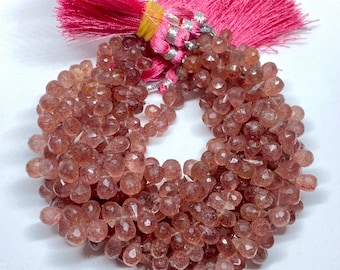 May include: A strand of faceted, translucent, pink and brown gemstone beads. The beads are approximately 6mm in size and have a slightly irregular shape. The beads are strung on a clear elastic cord and are ready to be used for jewellery making.