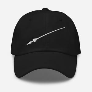 May include: A black baseball cap featuring a white embroidered graphic of a long, slender spear or lance positioned diagonally across the front panel. The cap has a structured crown, a curved brim, and a button at the top center of the dome.
