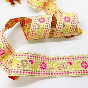 May include: A roll of white ribbon with pink and gold floral embroidery. The ribbon has a chequered pattern and is ideal for adding a touch of elegance to any project.