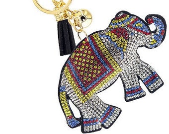 May include: A gold key chain with a black tassel and a rhinestone elephant charm. The elephant is decorated with red, yellow, blue, and white rhinestones.
