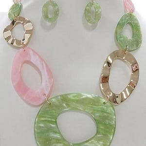May include: A green and pink statement necklace with large oval-shaped links. The necklace is made of plastic and has a gold-tone finish.
