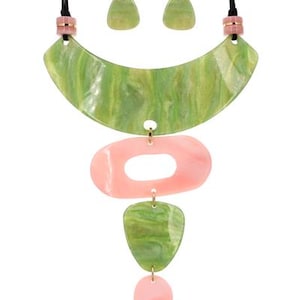 May include: A green and pink statement necklace with a large, curved green pendant and three smaller pendants. The necklace is made of resin and has a modern, geometric design.