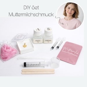 Op de afbeelding: DIY-set voor het maken van borstvoedingssieraden. De set bevat flessen met de tekst "Harz" en "Härter", spuiten, een hanger, een roze zakje met tekst en andere gereedschappen. De tekst "DIY Set Muttermilchschmuck" staat bovenaan.