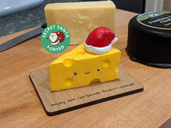 A Christmas tree ornament shaped like a charcuterie/cheese board — absurdly niche, instantly recognizable humor for the cheese-obsessed friend.