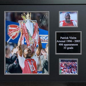 May include: A framed photo of Patrick Vieira, a former Arsenal player, holding up a trophy. The photo is surrounded by other photos and text that reads "Patrick Vieira, Arsenal 1996 - 2005, 406 appearances, 33 goals".