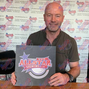May include: A man holds a black square sign with a white logo that says "www.allstarsignings.com". The logo is red, white, and blue and features a star and a circle.