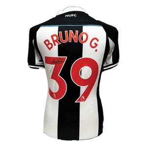 May include: A black and white striped soccer jersey with the name "BRUNO G." and the number "39" in red. The jersey has a "NUFC" logo on the collar and a signature. The jersey is a sports apparel item.