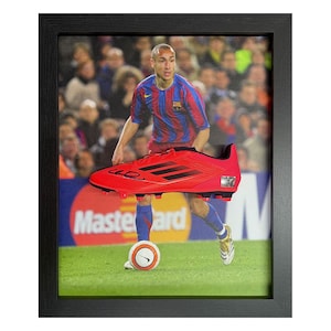 May include: Framed artwork featuring a soccer player in a red and blue jersey, with a red soccer cleat in the foreground. The background shows a stadium with spectators and a Mastercard logo.