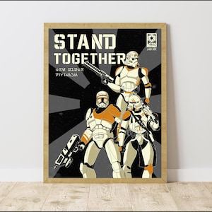 May include: A framed Star Wars poster with three clone troopers in white and orange armour, holding blasters. The poster has the words "STAND TOGETHER" in large letters, with a black and grey background.
