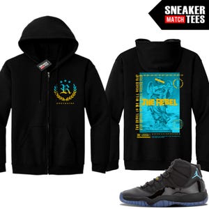 May include: Black zip-up hoodie with a front logo featuring a gold wreath and the letter "R". The back of the hoodie displays a graphic with the text "THE REBEL" and an angel statue. A pair of black and blue sneakers are also in the image.