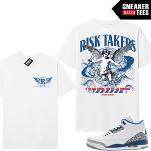 Pode incluir: Uma t-shirt branca de manga curta com um pequeno logótipo azul de um R alado no peito. As costas apresentam um grande gráfico de um querubim alado sobre um globo com o texto RISK TAKERS e IF YOU RISK NOTHING, THEN YOU RISK EVERYTHING.