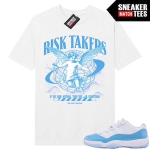 Puede incluir: Camiseta blanca con un gráfico azul claro de un ángel, un globo y el texto "RISK TAKERS". El texto "IF YOU RISK NOTHING, THEN YOU RISK EVERYTHING" está debajo. Un par de zapatillas blancas y azul claro están en la imagen.