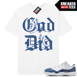 May include: White t-shirt with a blue graphic reading "God Did" in a stylized font, featuring angel illustrations. A tag reads "Sneaker Match Tees." Blue and white sneakers are in the foreground.