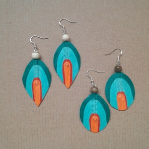 May include: Three pairs of teal, orange and white layered paper earrings with wooden beads. The earrings are shaped like teardrops.