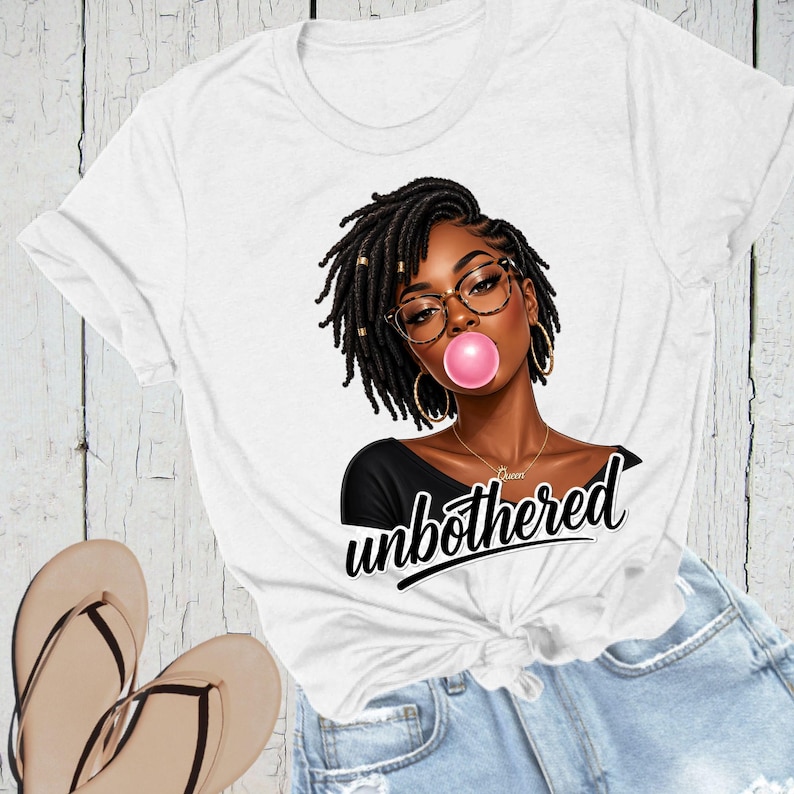 Puede incluir: Camiseta blanca con un gr&aacute;fico de una mujer negra con rastas, gafas y una burbuja de chicle rosa. La palabra "unbothered" est&aacute; escrita en cursiva debajo del gr&aacute;fico. La camiseta est&aacute; anudada a la cintura.