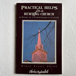 Puede incluir: Portada de libro con el título "PRACTICAL HELPS for a HURTING CHURCH" y el subtítulo "A Study of 1 Corinthians 6:12-11:34." La portada presenta una fotografía de una iglesia con una aguja rosa sobre un cielo azul. El nombre del autor, Charles R. Swindoll, está en la parte inferior.