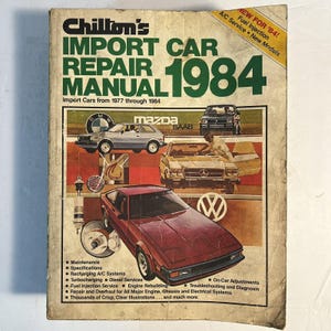 Puede incluir: Un manual de reparación de automóviles de importación Chilton's de 1984. La portada presenta un collage de coches, incluyendo un Mazda y un Saab, con el título en letras verdes grandes. El manual cubre coches de importación de 1977 a 1984.