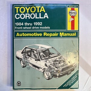 Puede incluir: Manual de reparación automotriz Toyota Corolla verde y blanco. La portada presenta el texto "TOYOTA COROLLA" y "1984 a 1992 Modelos de tracción delantera". El manual incluye un diagrama de un coche y el logotipo de Haynes.