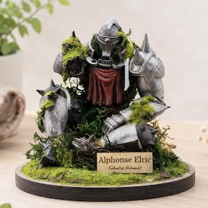 May include: A detailed figurine of Alphonse Elric from Fullmetal Alchemist, in silver armor, resting on a bed of green moss. A red cloth is visible at the chest. The figurine is on a round, black base with a small nameplate.