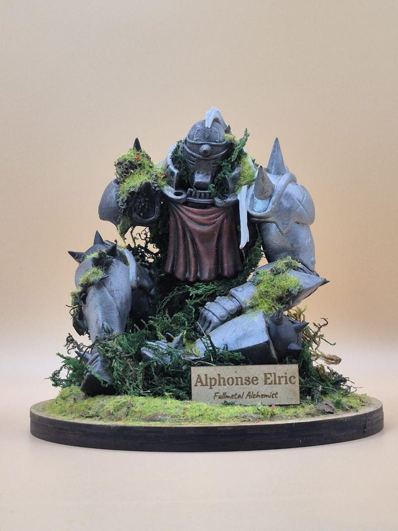 May include: A detailed figurine of Alphonse Elric from Fullmetal Alchemist, in a seated position, covered in moss. The figure is gray with a red cape and is mounted on a wooden base with a nameplate that reads "Alphonse Elric, Fullmetal Alchemist."