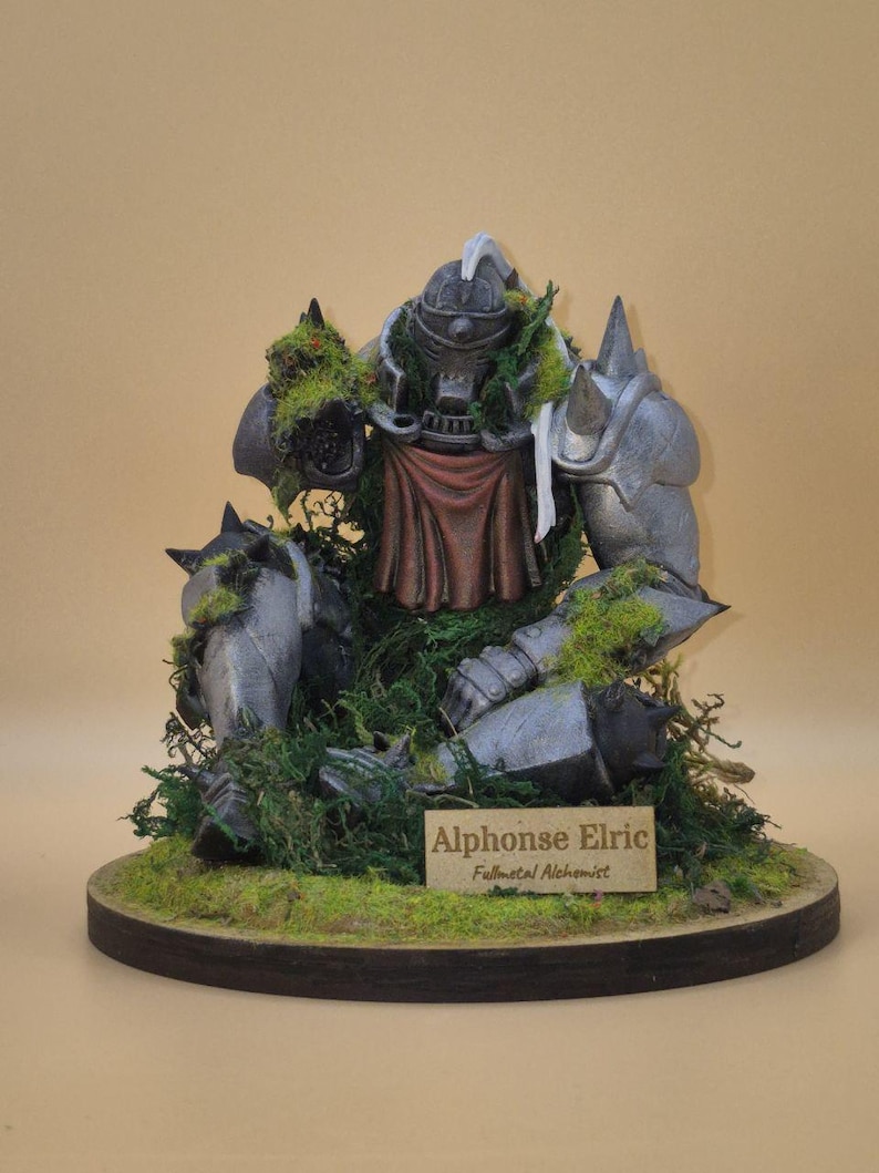 May include: A detailed figurine of Alphonse Elric from Fullmetal Alchemist. The figure is in a battle-worn state, with metallic armor, a red cloth, and patches of green moss. The base is a wooden circle with more moss and a nameplate.