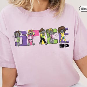 May include: A pink t-shirt featuring a graphic of five cartoon mice spelling out "SPICE MICE". The mice are wearing different coloured outfits and have different hairstyles.