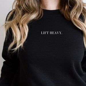 May include: Black sweatshirt with the text "LIFT HEAVY." in white lettering.