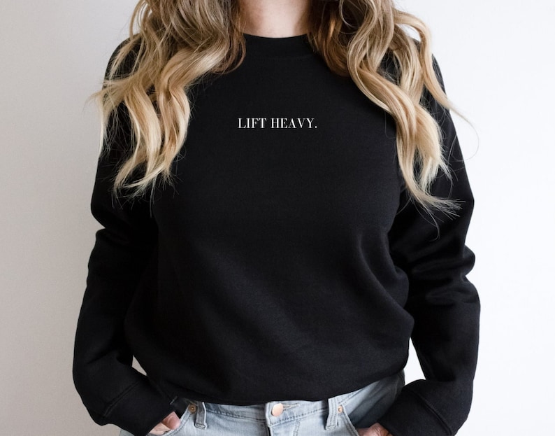 May include: Black sweatshirt with the text "LIFT HEAVY." in white lettering.