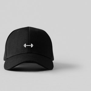 Könnte beinhalten: Schwarze Baseballkappe mit einem weißen Hantel-Motiv.