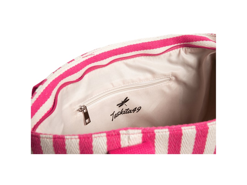 May include: Inside of a pink and white striped tote bag with a zippered pocket and the text "Taskita49" with a dragonfly logo.